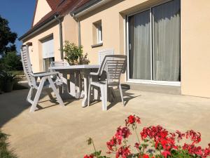 a table and chairs on a patio with red flowers at Charmant gîte cozy près du Mans avec jardin, terrasse, proche commodités et activités. - FR-1-410-336 in Rouillon