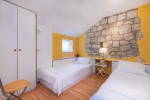 a bedroom with two beds and a stone wall at Holiday house with a swimming pool Podobuce, Peljesac - 21882 in Orebić +19 photos