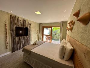 a bedroom with a bed and a tv on a wall at Kaçuá Milagres in São Miguel dos Milagres