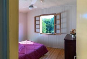 Casa aconchegante no Vale Vinhedos في بينتو جونكالفيس: غرفة نوم بسرير ارجواني ونافذة