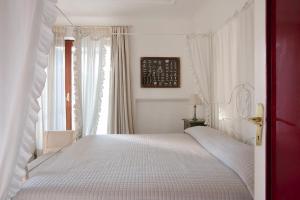 a bedroom with a white bed and a window at Villa Gianturco - Luxury In The Green Island in Ischia