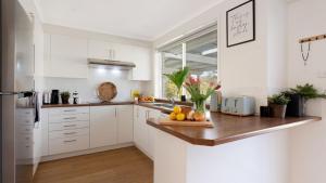 a kitchen with white cabinets and a wooden counter top at Salty Marlin in Callala Bay