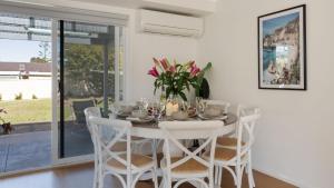 a white dining room with a white table and chairs at Salty Marlin in Callala Bay