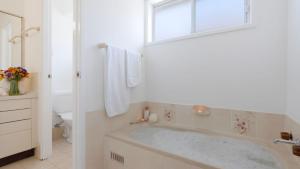 a white bathroom with a tub and a window at Salty Marlin in Callala Bay