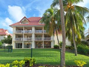 une grande maison avec des palmiers en face de celle-ci dans l'établissement Le MaDja'Kaz - studio en résidence et bord de Mer - Sainte Luce Martinique, à Sainte-Luce