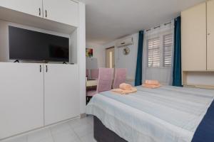 ein Schlafzimmer mit einem Bett und einem Flachbildfernseher in der Unterkunft Apartments by the sea Balica Rat, Omis - 1065 in Omiš