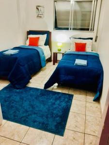1 dormitorio con 2 camas con sábanas azules y almohadas rojas en Apto Amplo, confortável, bem localizado, Astúrias en Guarujá