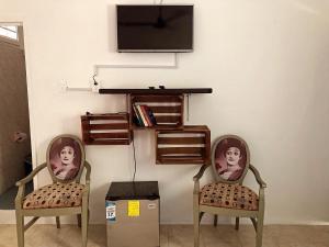 two chairs with a television on a wall at Posada DORA in Isla Mujeres