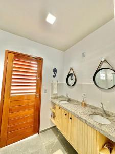a bathroom with two sinks and a wooden door at Noah Hostel & Chale in São Miguel do Gostoso