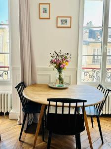 una mesa de comedor con un jarrón de flores. en Charmant Appartement - Découvrir la Ville Lumière en París