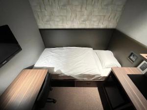 małe łóżko w małym pokoju z dwoma biurkami w obiekcie Tanegashima Araki Hotel w mieście Nishinoomote
