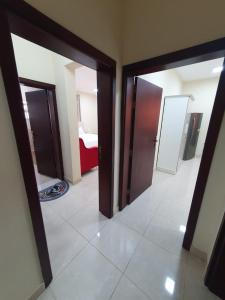 a hallway with two doors and a room with a bed at Terhal salalah 1 in Salalah