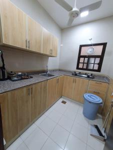 uma cozinha com armários de madeira e uma lata de lixo azul em Terhal salalah 1 em Salalah