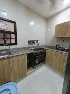 a kitchen with wooden cabinets and a stove top oven at Terhal salalah 1 in Salalah