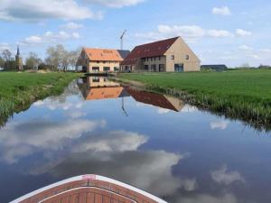 a boat traveling down a river with houses and buildings at 20-person group home in the heart of Friesland in Leons