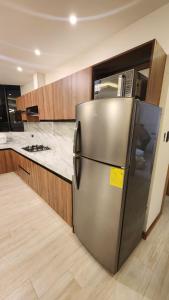 een roestvrijstalen koelkast in een keuken met houten kasten bij 203 La Terraza departamento in Cuenca