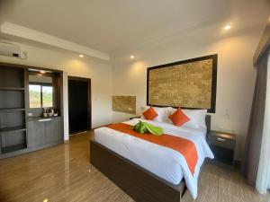 a bedroom with a large bed with an orange blanket at The Hamsa in Lovina