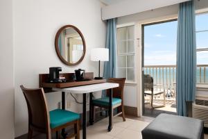 a room with a desk and chairs and a balcony at Sand Rose Beach Resort in South Padre Island