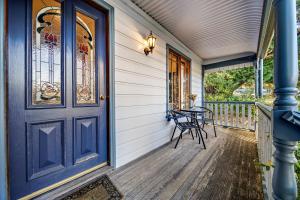 a front porch with a blue door and chairs at Whispering Pines Cottages in Wentworth Falls