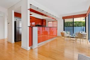 una cucina a pianta aperta con armadi rossi e frigorifero in acciaio inossidabile di Escape to Clear Island - A Palmy Waterfront Oasis a Gold Coast