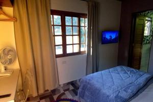 um quarto com uma cama, uma janela e uma televisão em Casinha acolhedora da mata - Rota do Vinho em São Roque