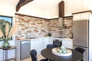 a kitchen with white cabinets and a black table at Onetangi Beach Stays Apartment - Coast & Country in Onetangi
