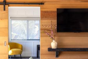 a living room with a television and a vase with flowers at Onetangi Beach Stays Apartment - Coast & Country in Onetangi