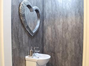 a bathroom with a sink and a heart shaped mirror at The Old Blue Shop in Milford Haven