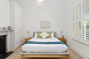 a white bedroom with a bed and a fireplace at Boutique Stays - Alkira House in Melbourne