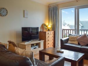 a living room with a couch and a tv and a table at Ty Celyn in Broad Haven