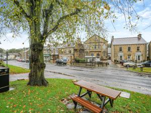 a park bench next to a tree and a street at East View House in Middleton in Teesdale