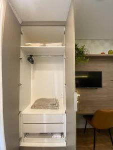 um armário com prateleiras brancas e uma televisão num quarto em Apartamento em São Paulo (Rosabianco) em São Paulo