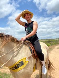 a man riding a horse with a hat on at Fazenda Terra Bonita - Passeios a Cavalo e Trilhas in Serra de São Bento