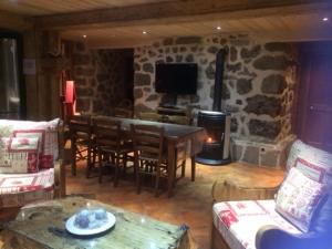 - un salon avec une table et une cheminée en pierre dans l'établissement Appartement Montagnard avec Sauna, Terrasse & Poêle à Bois - Proche Pistes et Commerces - FR-1-467-87, au Grand-Bornand