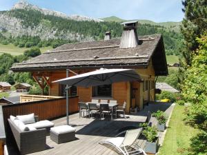 ein Haus mit einer Terrasse mit Stühlen und einem Sonnenschirm in der Unterkunft Grand appartement 9 pers, proche des pistes, Le Grand-Bornand - FR-1-467-57 in Le Grand-Bornand