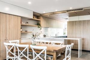 a kitchen with a wooden table and white chairs at A Perfect Stay - 11 James Cook Apartments in Byron Bay
