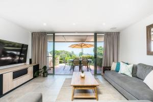 a living room with a couch and a table at 11 James Cook Apartments - w. pool & beach access in Byron Bay