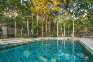 a blue swimming pool with trees in the background at A Perfect Stay - 11 James Cook Apartments in Byron Bay