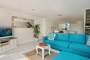 a living room with a blue couch and a tv at A Perfect Stay - 2 James Cook Apartments in Byron Bay