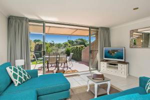a living room with a blue couch and a television at A Perfect Stay - 2 James Cook Apartments in Byron Bay