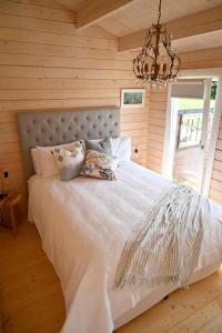 a bedroom with a large white bed with a chandelier at Avocate' Cottage in Whiritoa