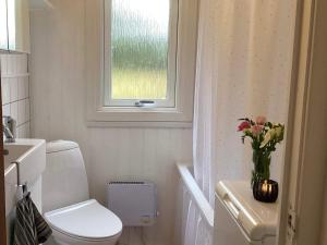 ein Bad mit einem WC, einem Fenster und einer Vase aus Blumen in der Unterkunft 4 person holiday home in Blokhus-By Traum in Blokhus + 35 Fotos