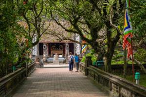 two people walking on a bridge in front of a temple at Ninh Binh Greenland Homestay in Ninh Binh