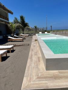 a swimming pool with benches next to a beach at Boca de agua Villas in Nautla