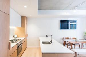 een keuken met een wit aanrecht en een tafel bij Cozy 2 Beds Apartment In Fitzroy For Rest And Work in Melbourne