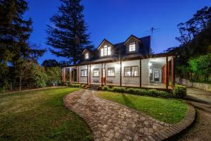 a large house with a brick driveway at Whispering Pines Cottages in Wentworth Falls