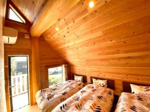 two beds in a room with wooden walls at 木の王様イェローシーダー ポーラーハウスカナディアン西軽井沢1 in Kutsukake
