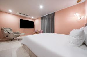麗水的住宿－Browndot Hotel Yeosu Yeocheon，卧室配有一张白色大床和电视。