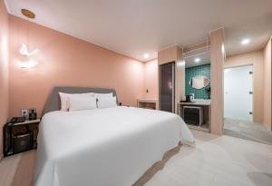 una camera con un grande letto bianco e un bagno di Browndot Hotel Yeosu Yeocheon a Yeosu