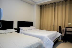 2 łóżka w pokoju z zasłonami w obiekcie Hotel Prado w mieście Huancayo